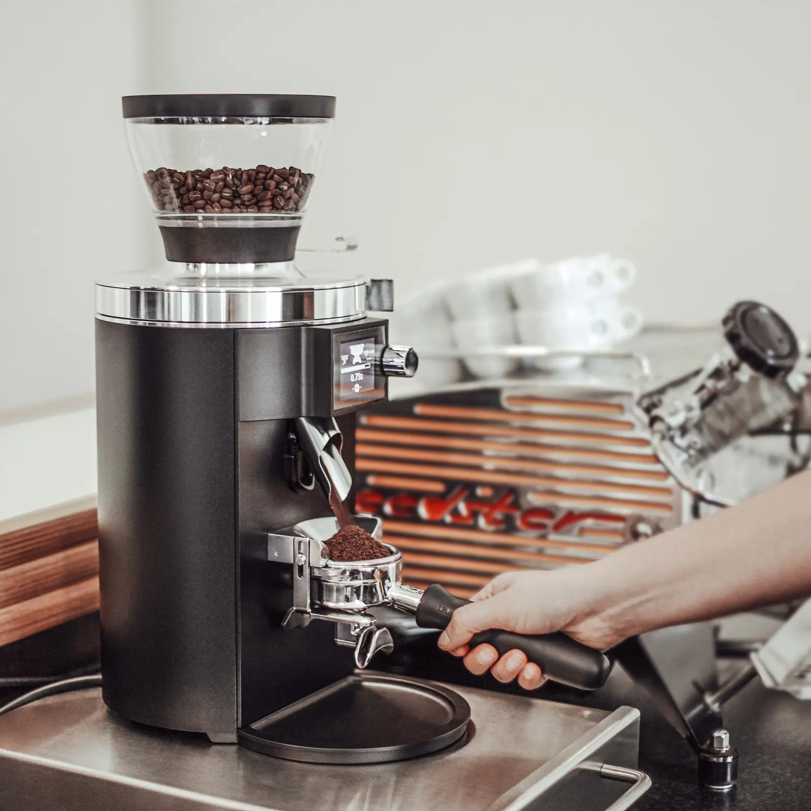 Barista mieli kawę do kolby na młynku Mahlkönig E65S obok ekspresu